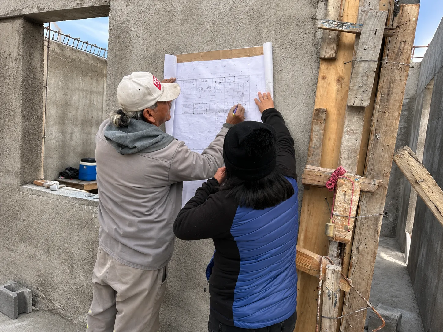 Dos técnicos revisando un plano contra la estructura en obra